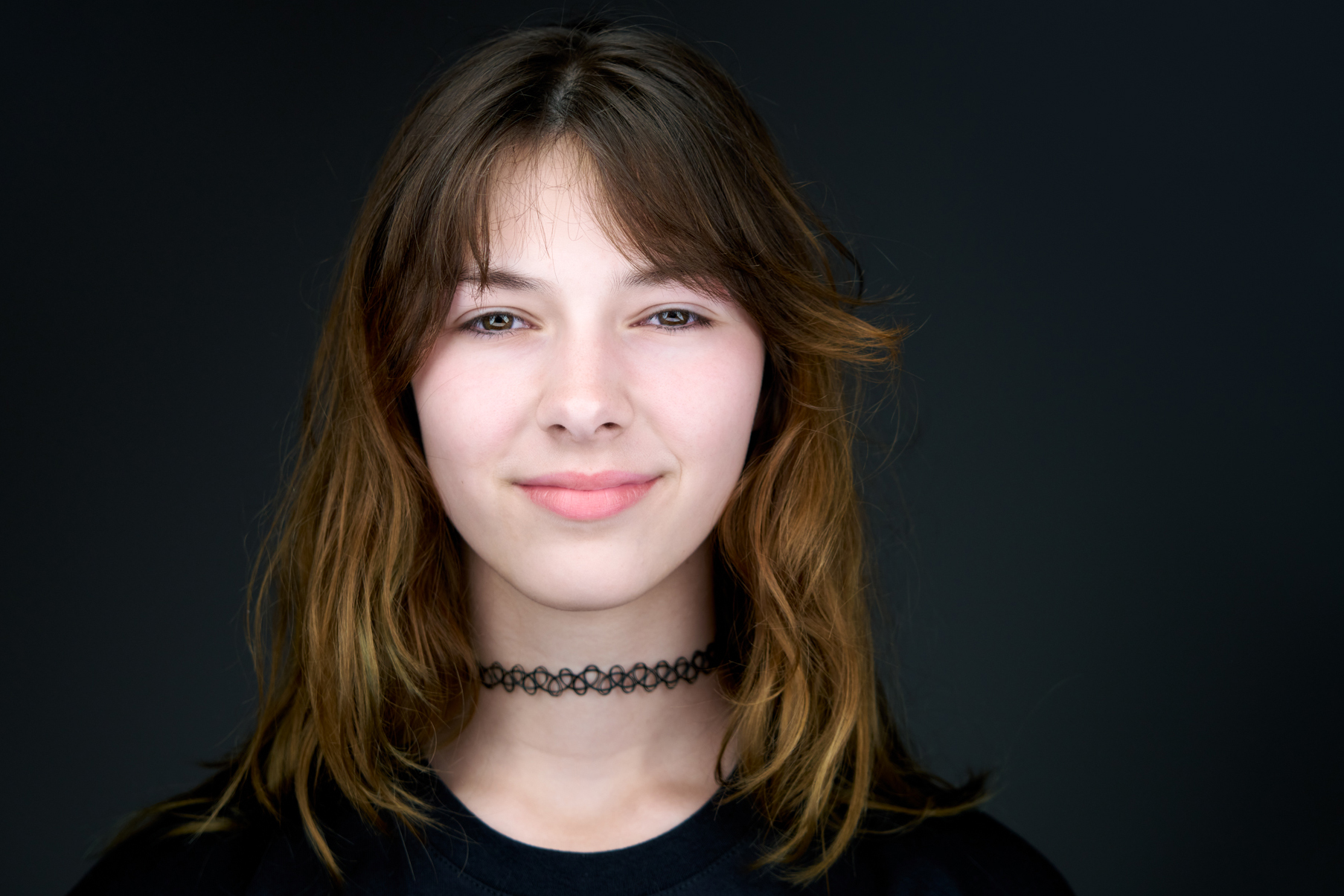 Studio headshot of a young woman with curly hair