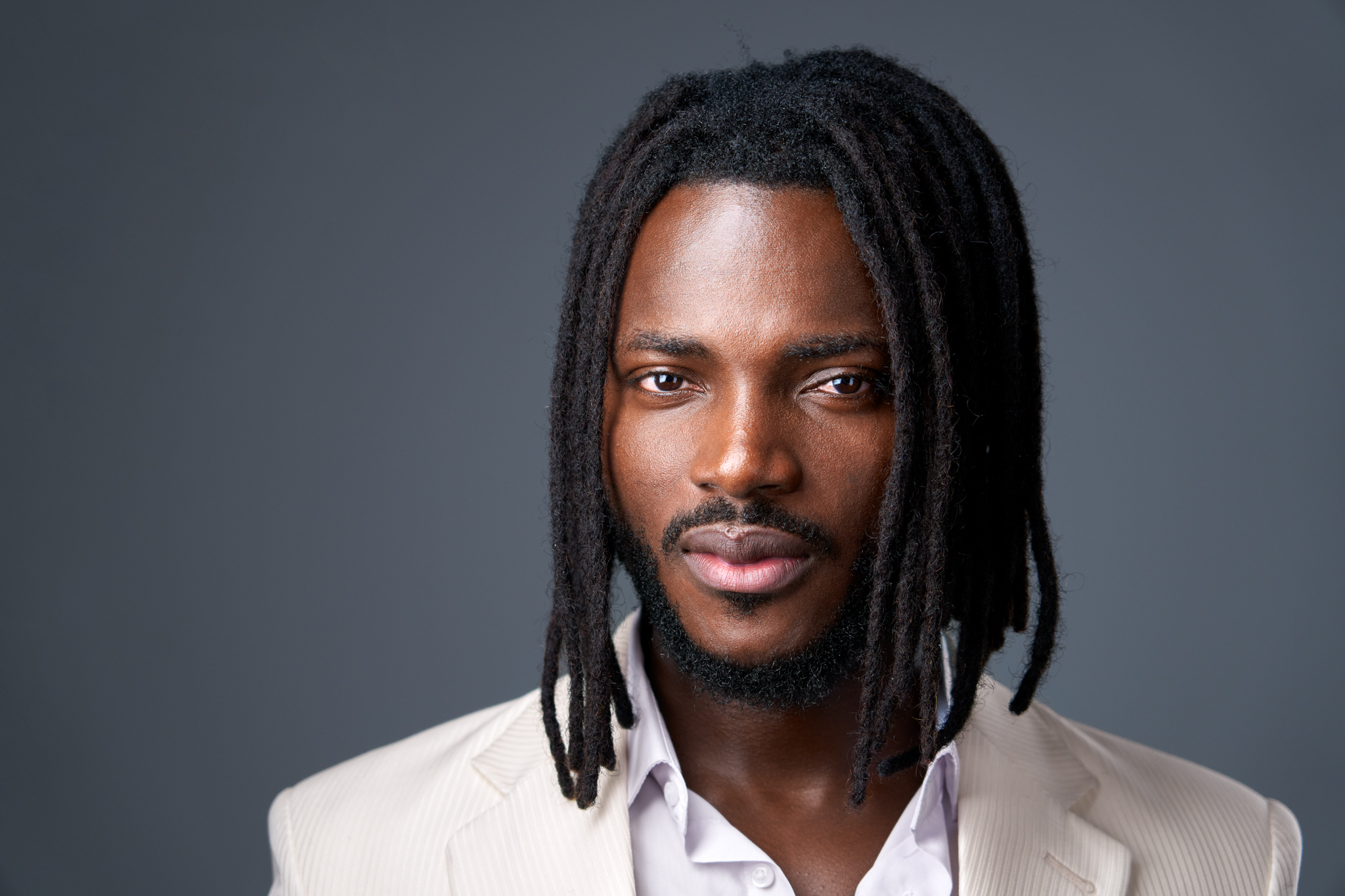 Studio headshot of a man with locs