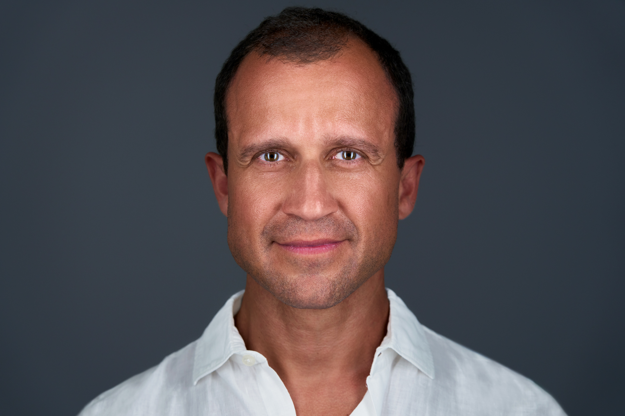 Studio headshot of a man in a white shirt