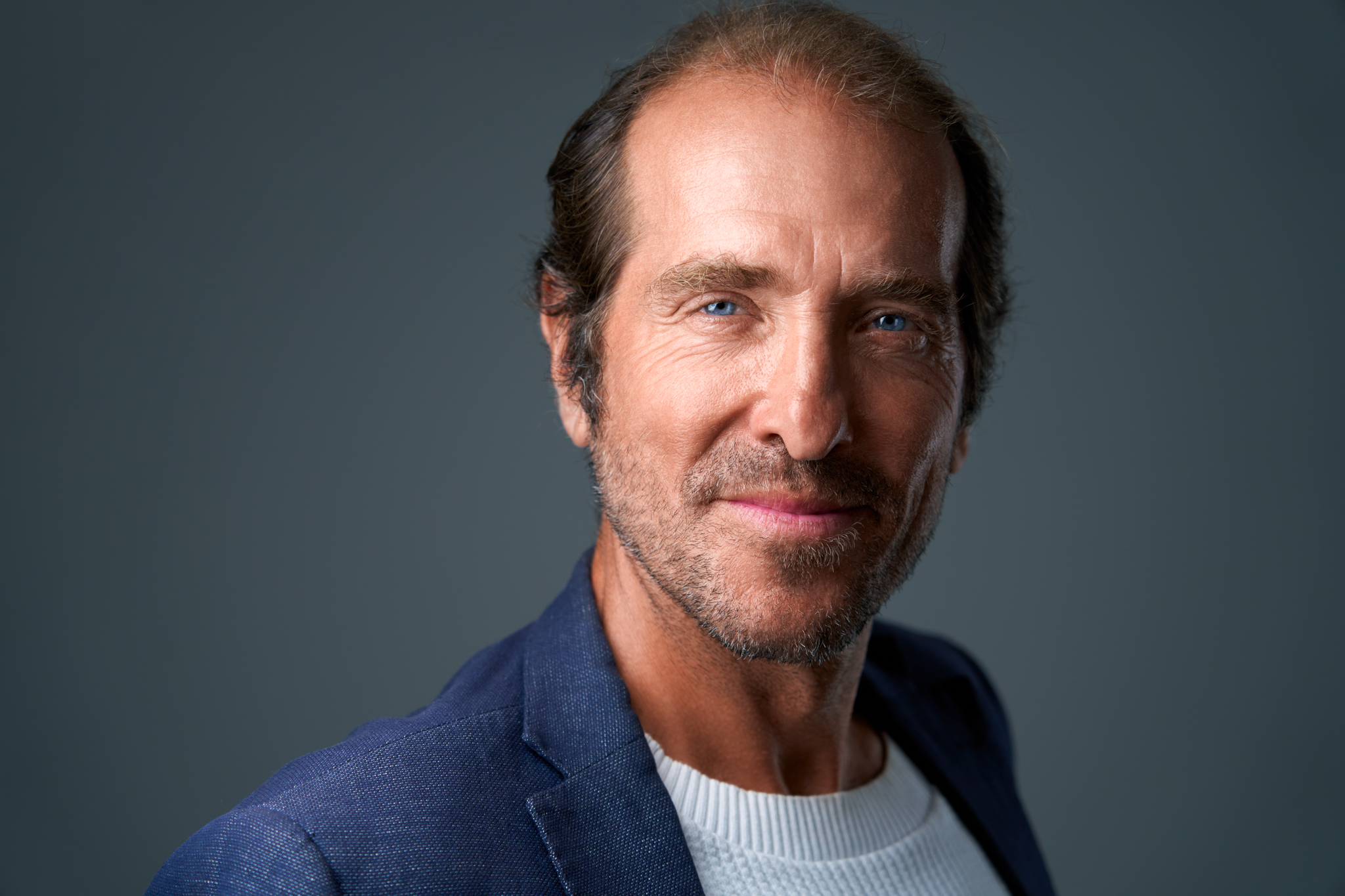 Studio headshot of a man in a blue jacket